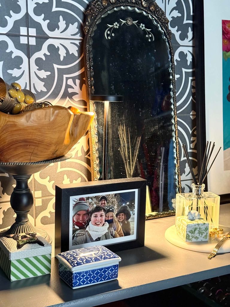 An antique mirror, touch lamp, and a reed diffuser placed as decorative accents on a closet vanity top.