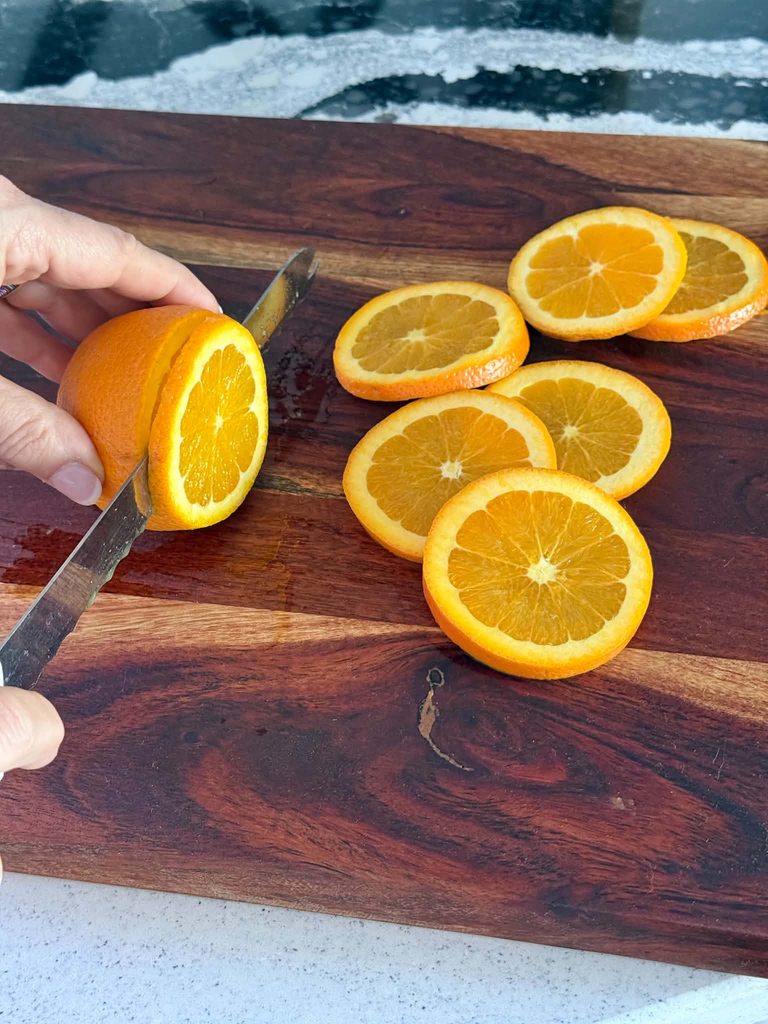 Slicing orange slices on a wood cutting board.