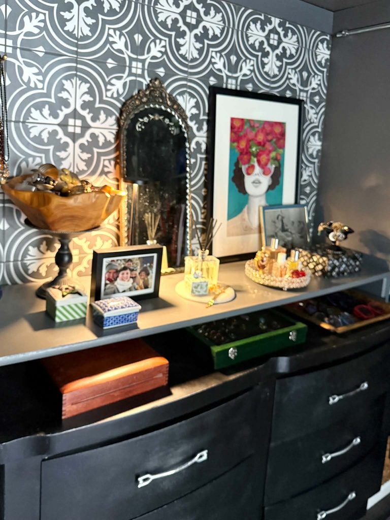 A walk-in closet dresser decorated with jewelry, perfume bottles, and a mirror.