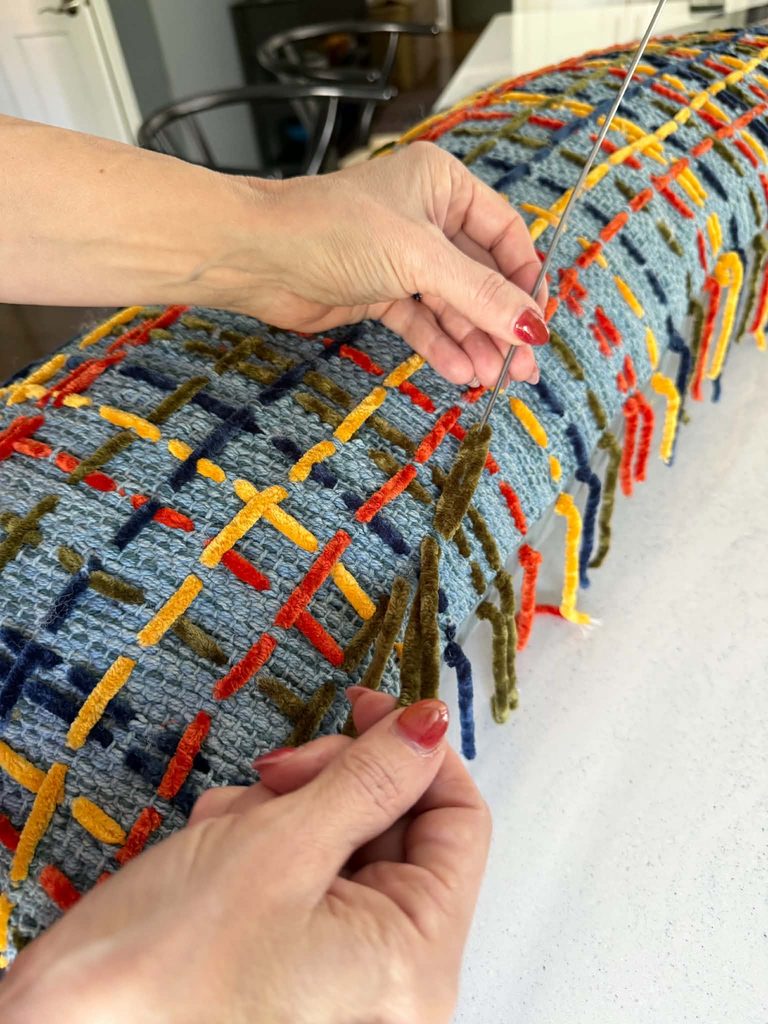 Stitching a plaid pattern on a decorative throw pillow.