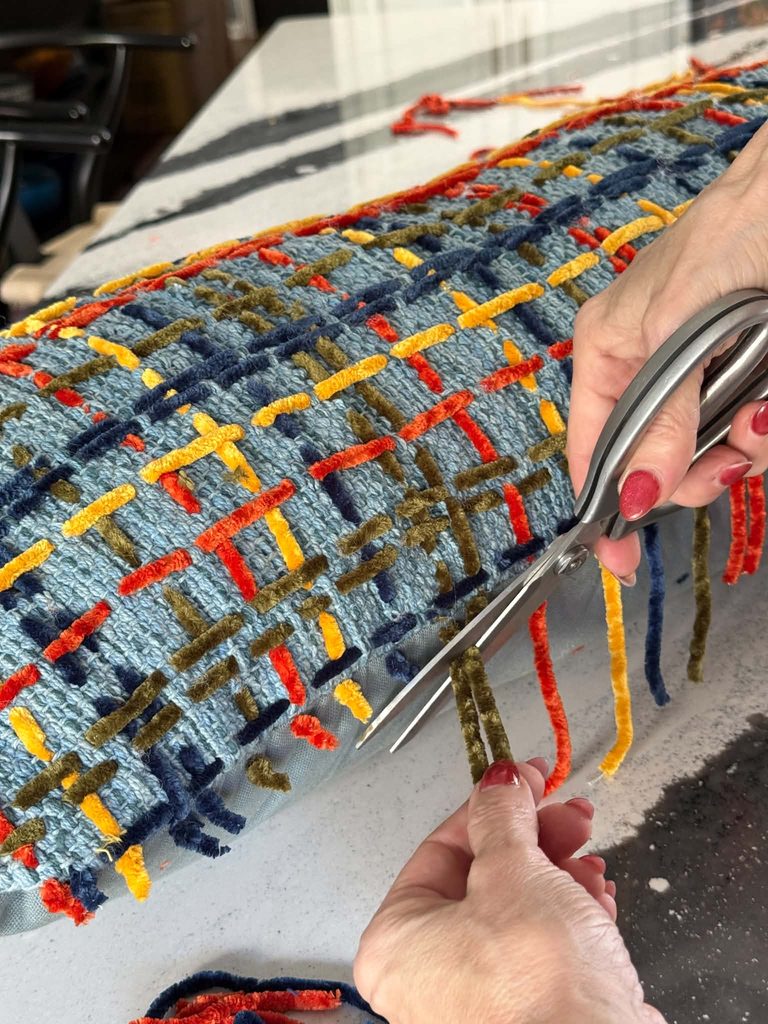 Cutting excess yarn from a stitched pillow.