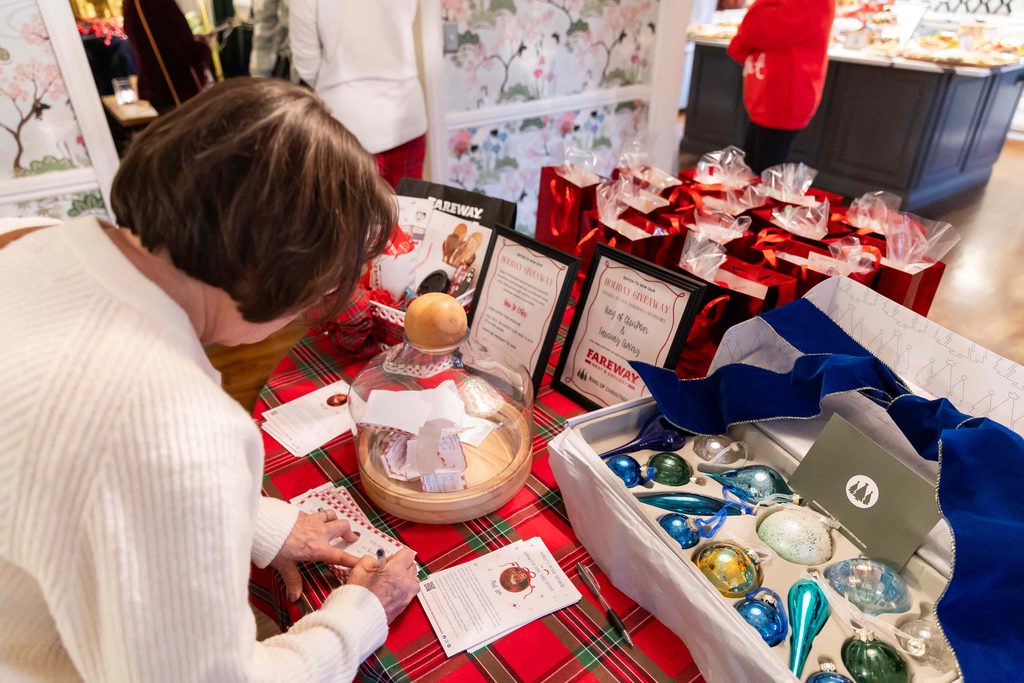 A woman filling out a drawing card for a holiday party giveaway.