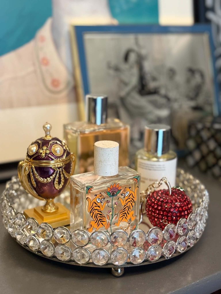 A glass vanity tray holding bottles of perfume.