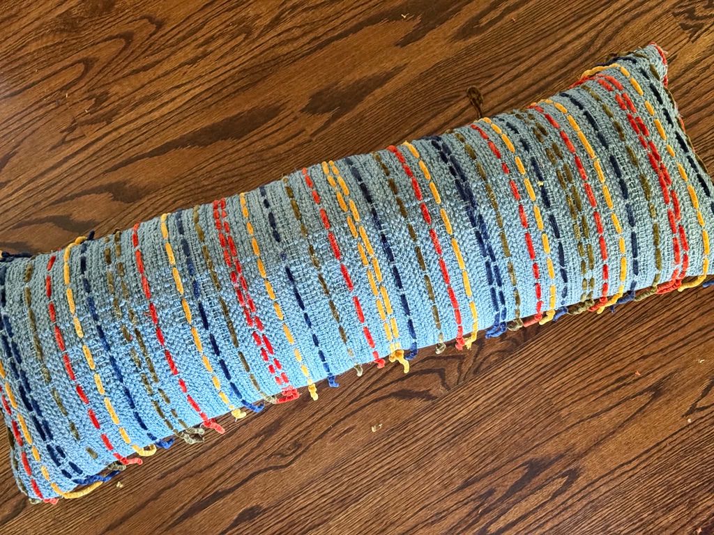 Chenille yarn stitched stripes that are decorating throw pillows.