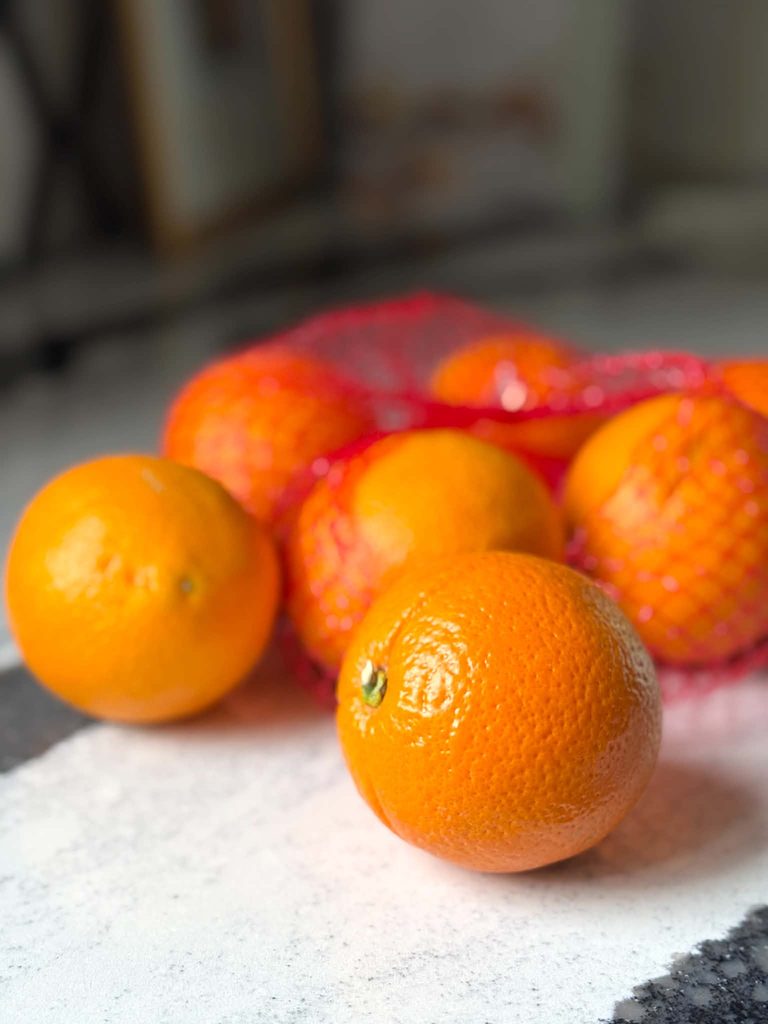 A dozen oranges on a kitchen counter.