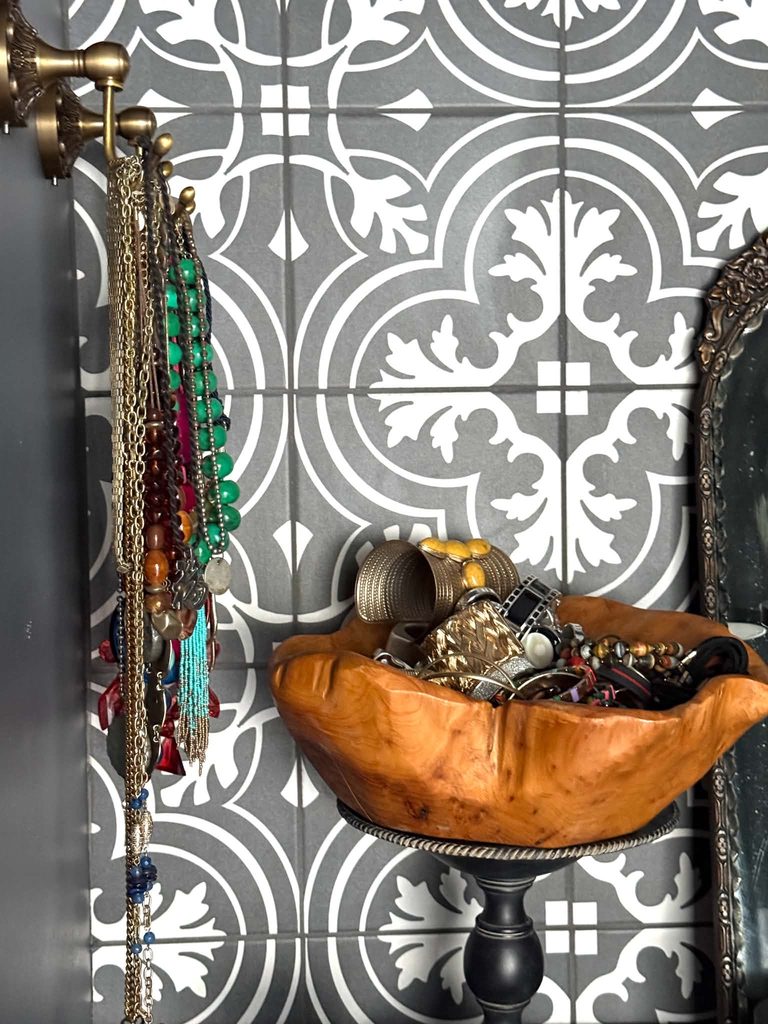 A wood bowl full of jewelry sitting on a walk-in closet vanity.